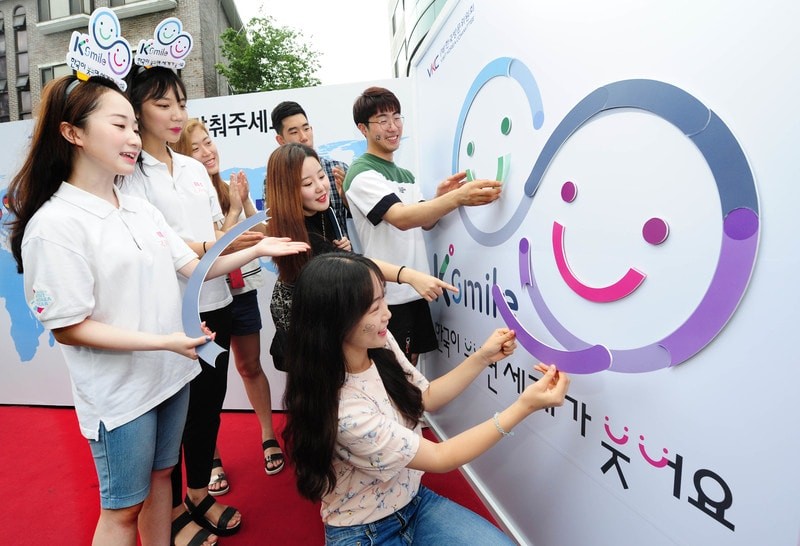 University Students’ National Smile Team members and citizens participating in the K-Smile emblem puzzle game&gt